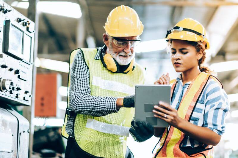 Two workers wearing protective clothing viewing a tablet, What is EHS Software | Be-Safe